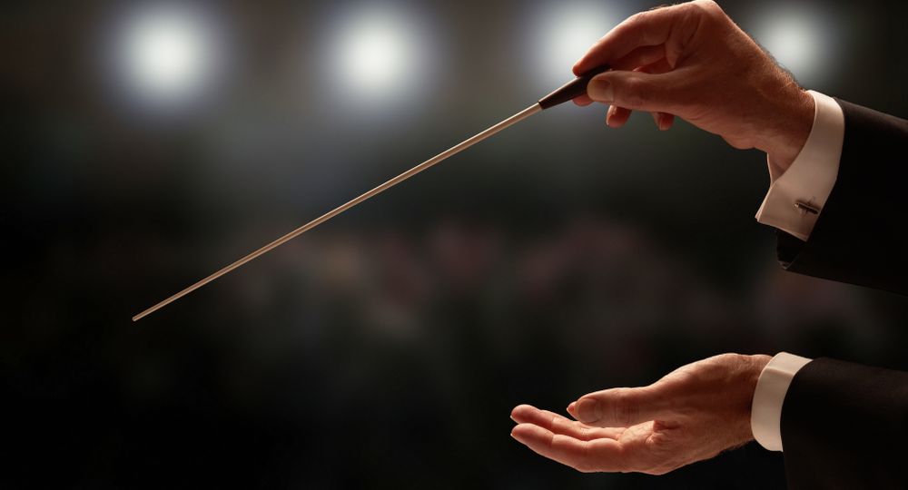 Conductor,Conducting,An,Orchestra,With,Audience,In,Background