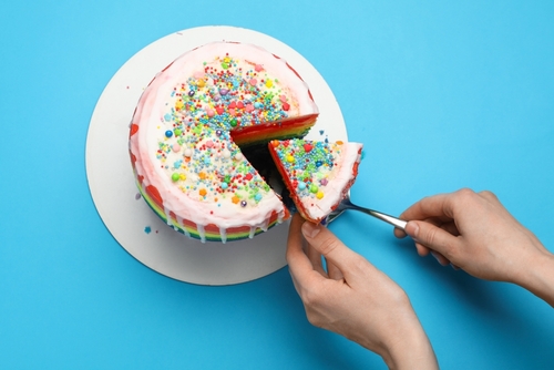 Woman,Taking,Piece,Of,Delicious,Rainbow,Cake,With,Spatula,At